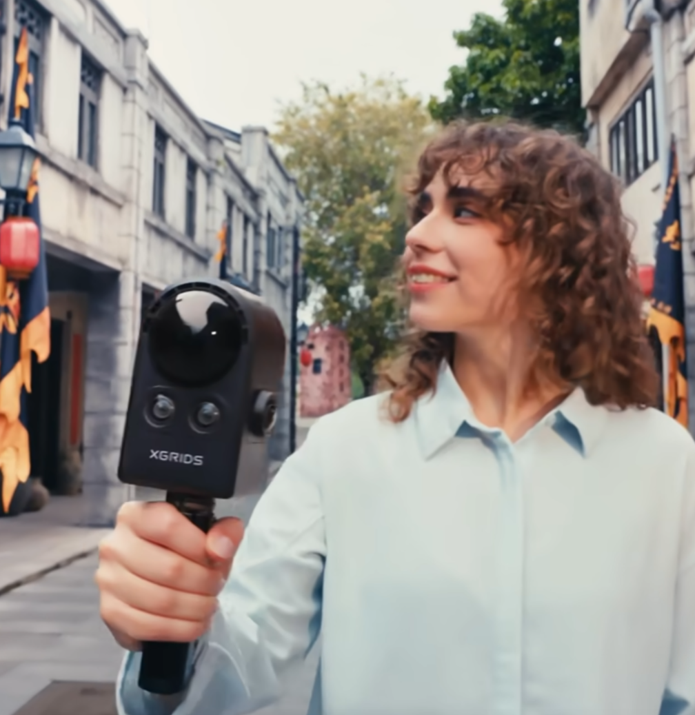 Operator walking with a handheld XGRIDS PortalCam spatial camera, capturing a site in a single mobile walkthrough.