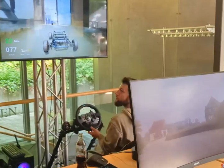Developer using a racing-wheel controller to drive through a scanned real-world environment turned into a playable game world.